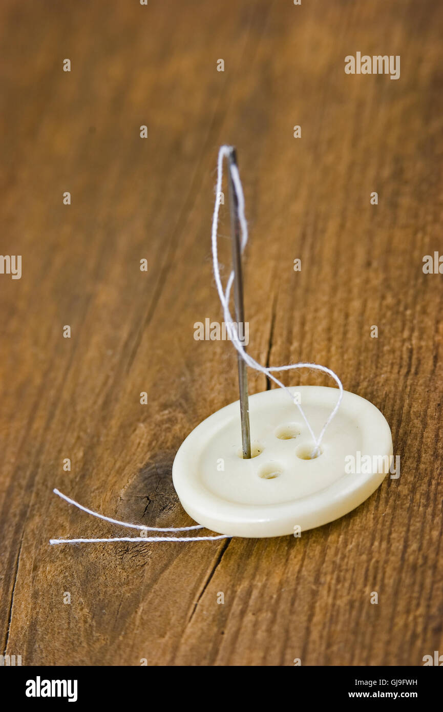 Buttons with needle and thread Stock Photo - Alamy