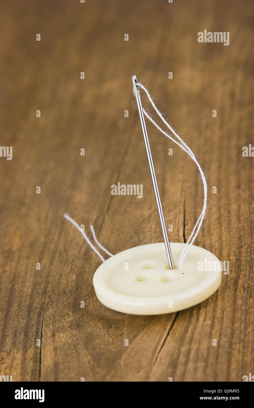 Buttons with needle and thread Stock Photo - Alamy