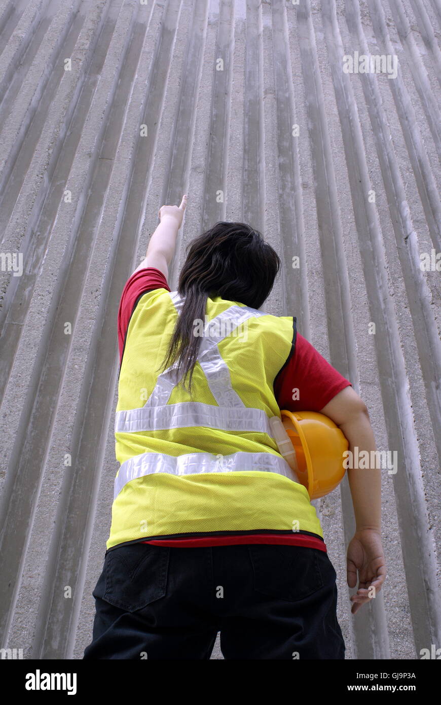 Asian contractor pointing upwards with half finished wall Stock Photo