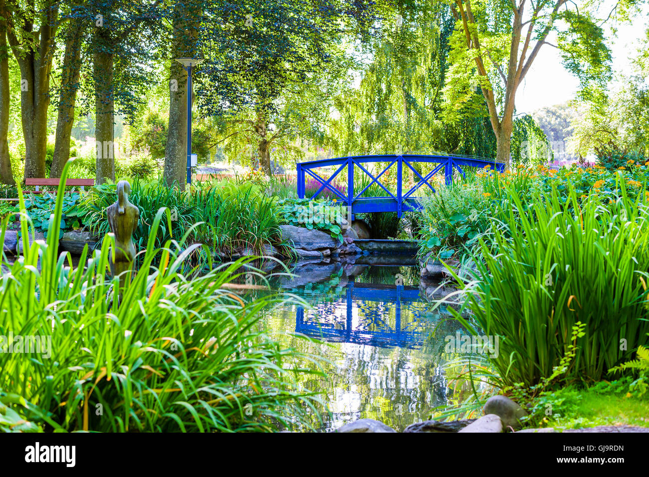 Kalmar, Sweden - August 10, 2016: A small blue bridge across a small pond in the public city park, Stadsparken. Trees in backgro Stock Photo