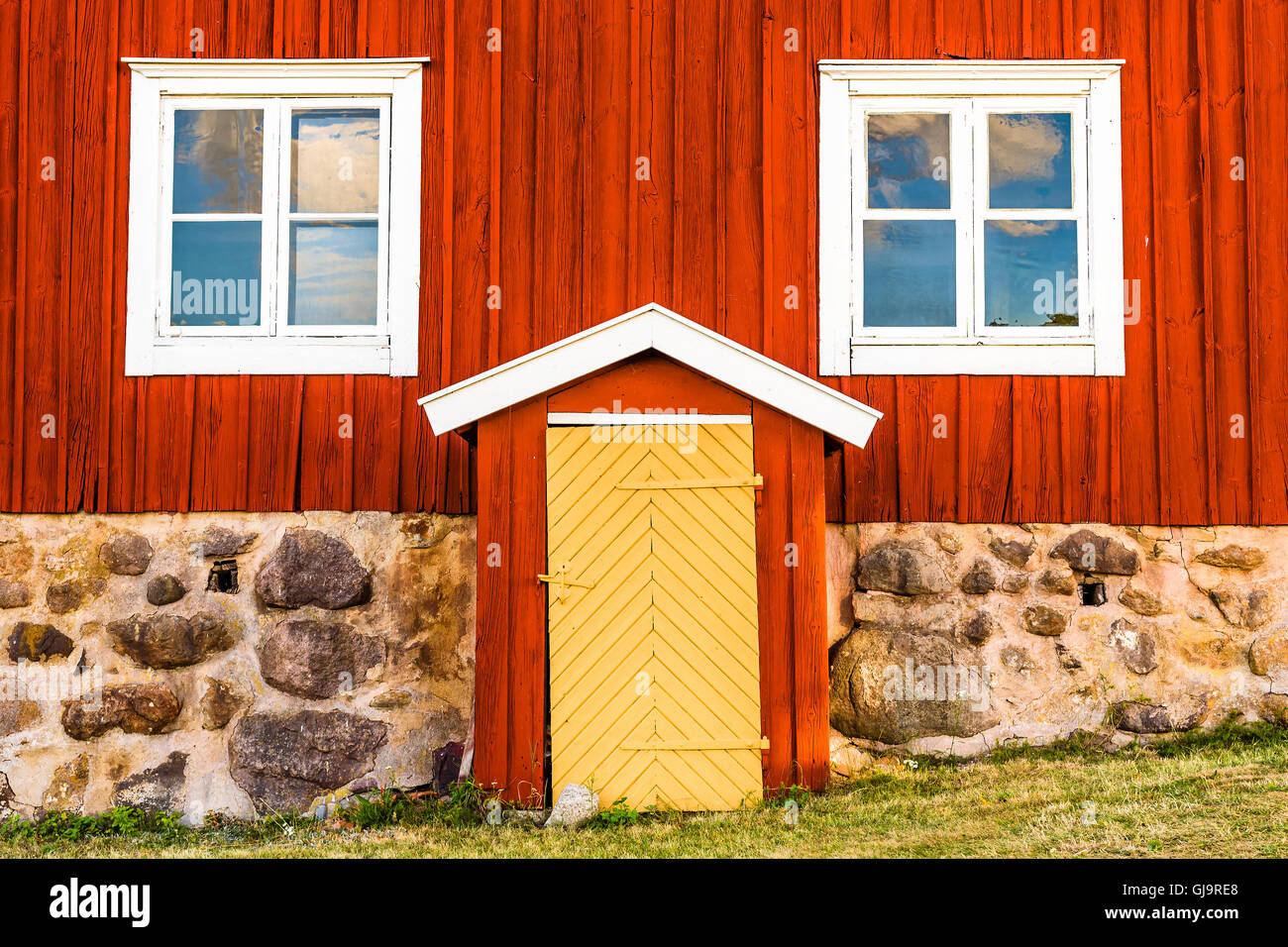 Lovely vintage yellow door on a bright red house with white details. Stock Photo