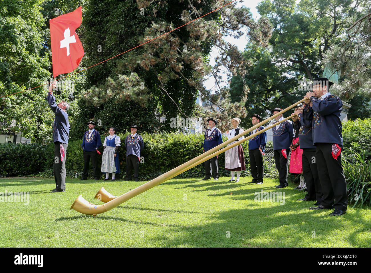 Members of the Trachtenvereinigung, two AlphornBlasers and a Fahnenschwinger perform in Zurich on Swiss National Day. Stock Photo
