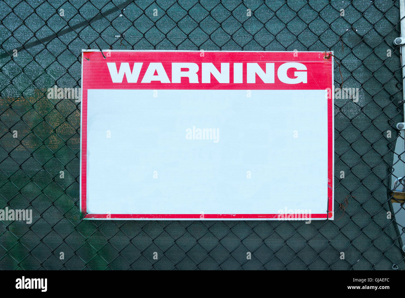 Warning Sign safety caution with blank white message at construction site grid boundary. Stock Photo