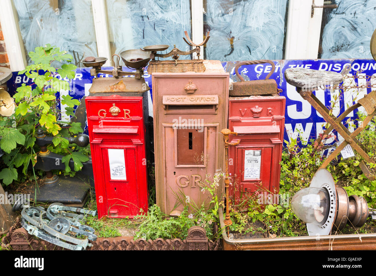 Old red post boxes on display in the courtyard of an antique shop in