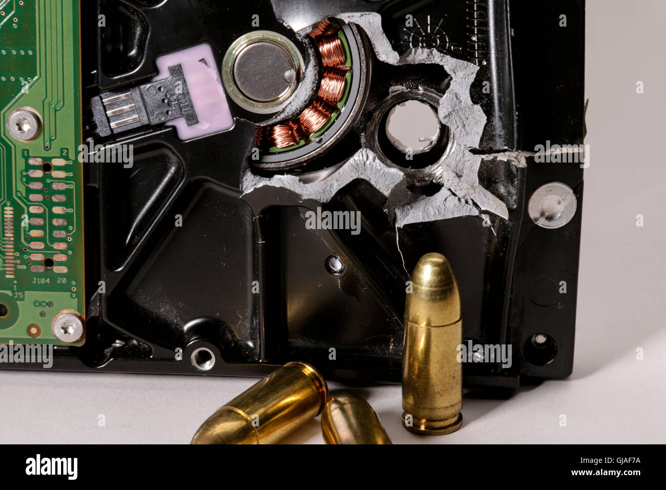 Computer hard drive with bullet hole and 9mm bullets. Stock Photo