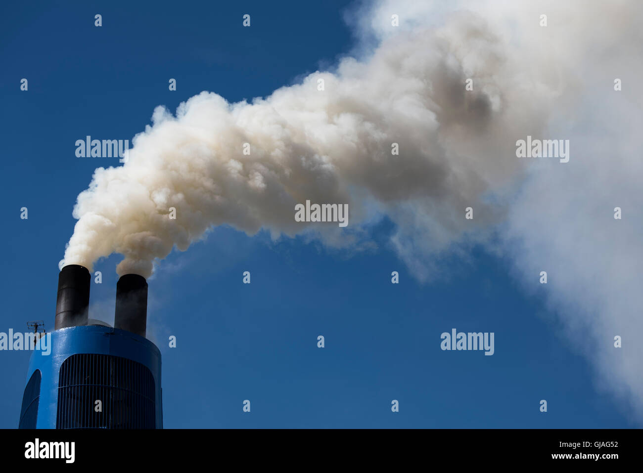 boat chimney in action, lot of pollution, white smoke against a blue sky Stock Photo