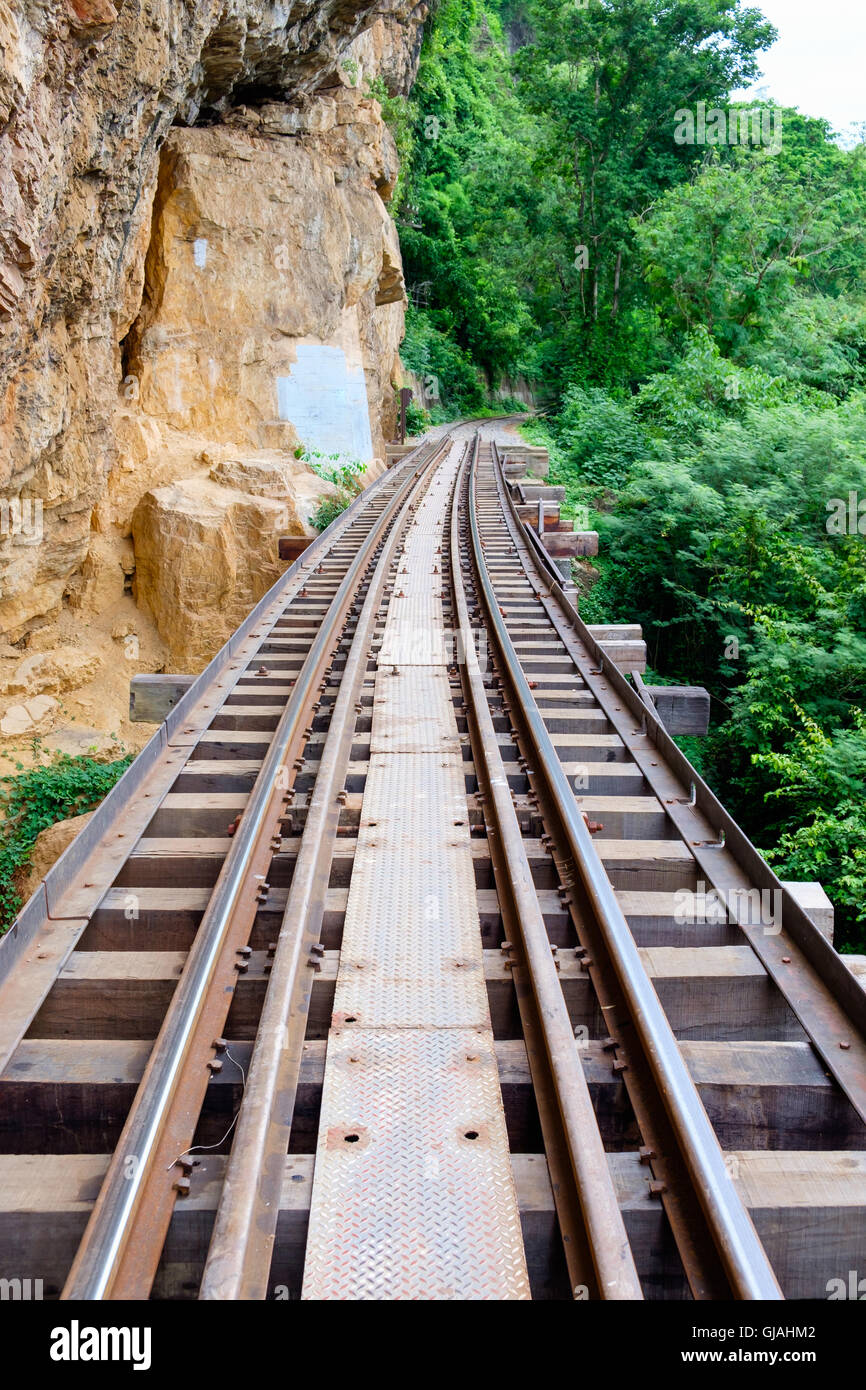 The Death Railway bridge along the cliff and tree located at Kanchanaburi, Thailand. Stock Photo