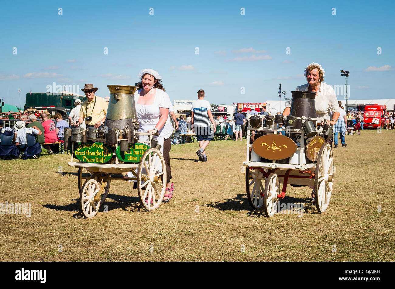 Two period milkmaids pushing milk carts with churns at an English show Stock Photo