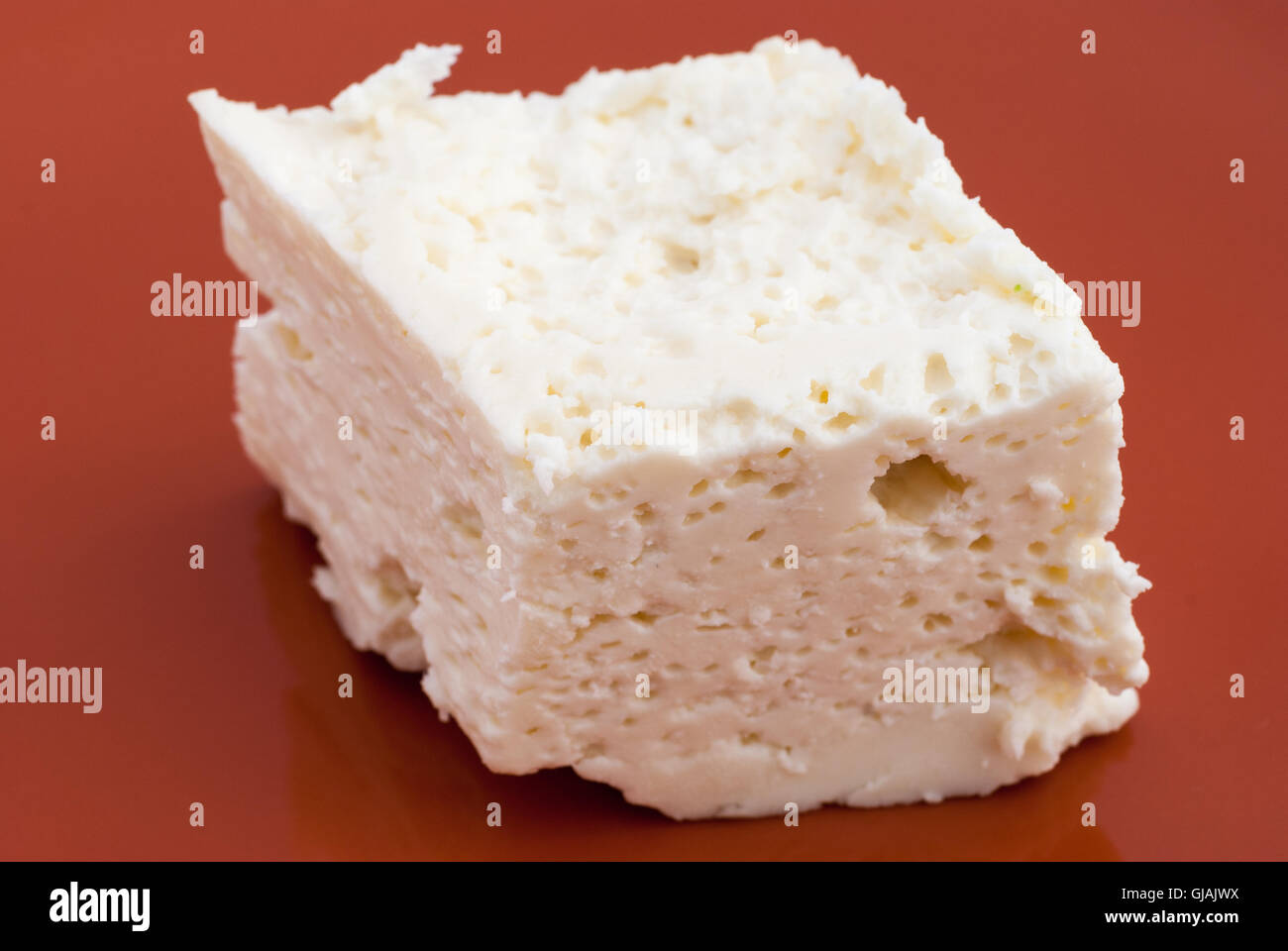 Piece of traditional Romanian cheese brinza (branza) on a brown background closeup Stock Photo