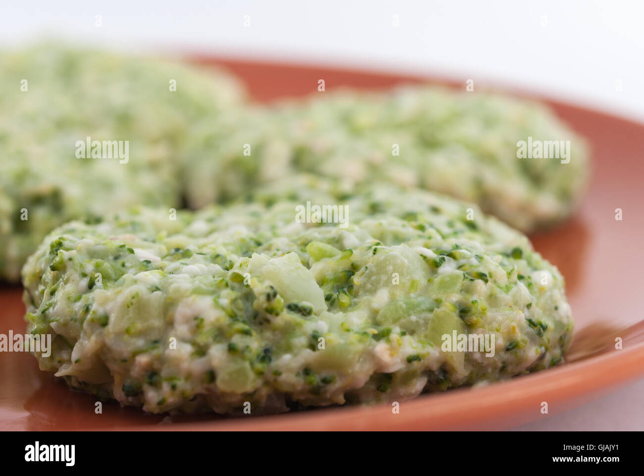 Raw broccoli and cheese pancakes on a brown plate closeup. Stock Photo