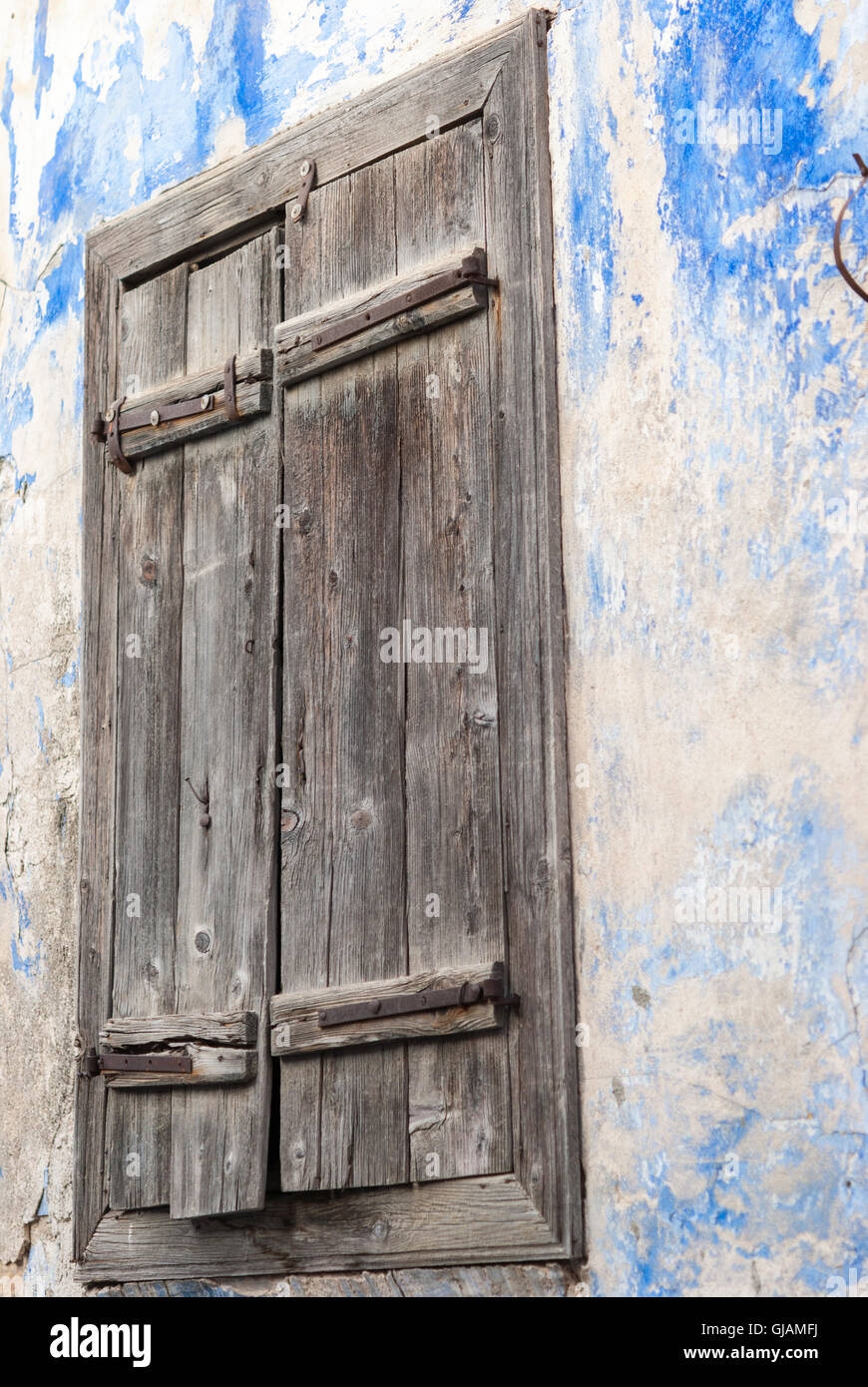 Closed old rustic shabby grey wooden shutters on a stone house wall ...
