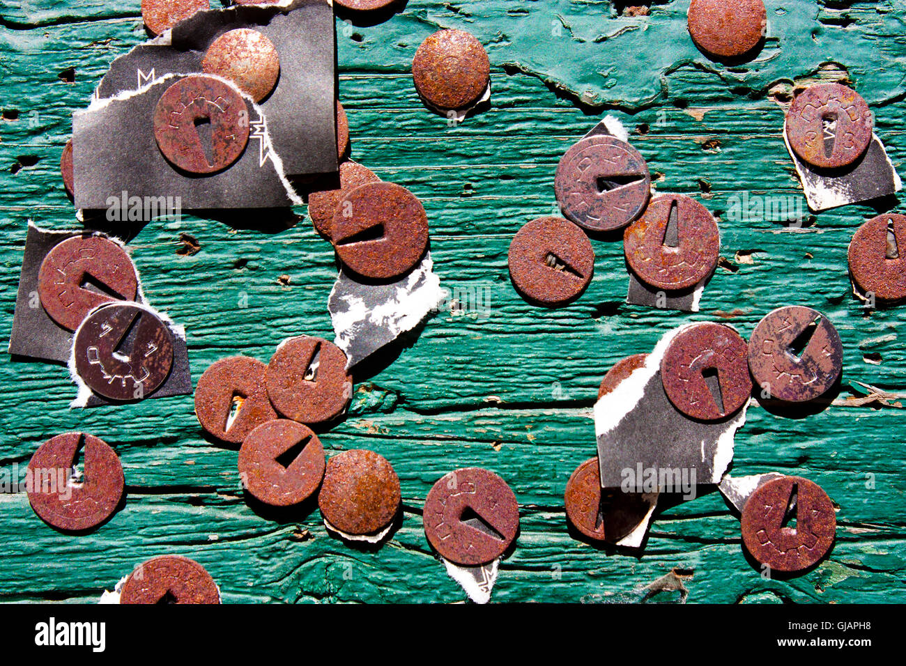 Rotten thumbtacks on green scratched wooden board with torn peaces of old announcements and notices Stock Photo