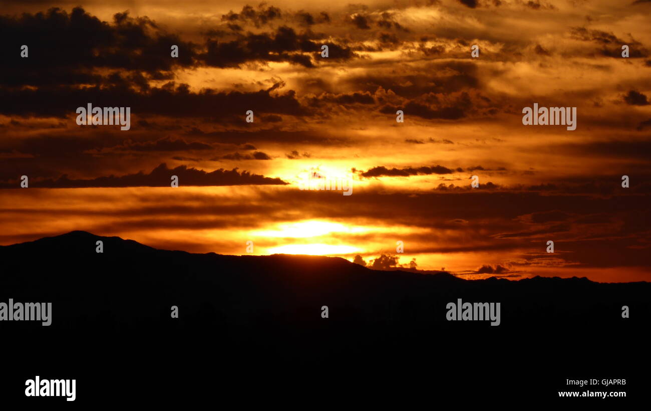 Dark ominous sunrise in the desert with various cloud layers Stock Photo