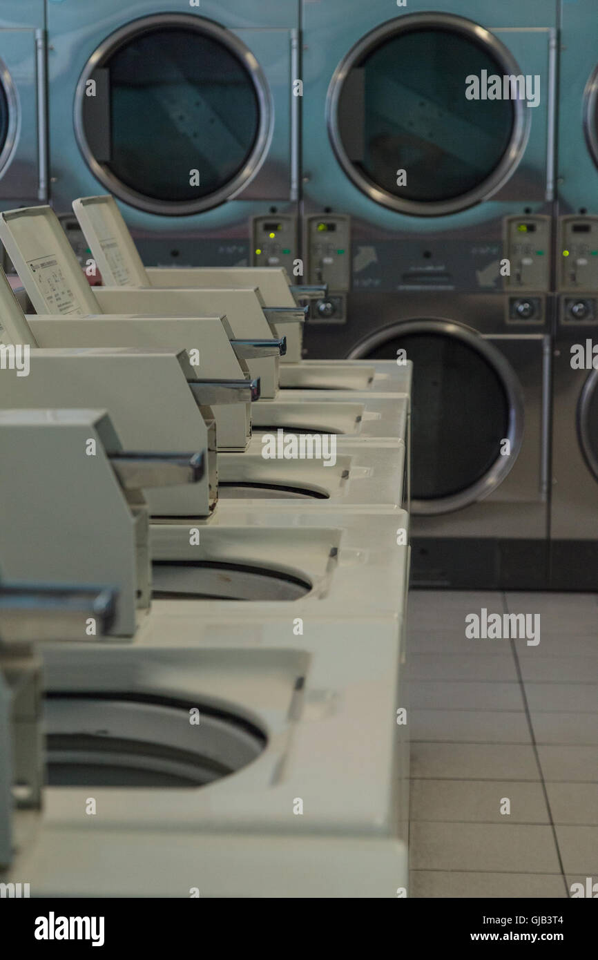 Washing clothes and drying at the Laundromat with chrome washer and dryer units along the isle
