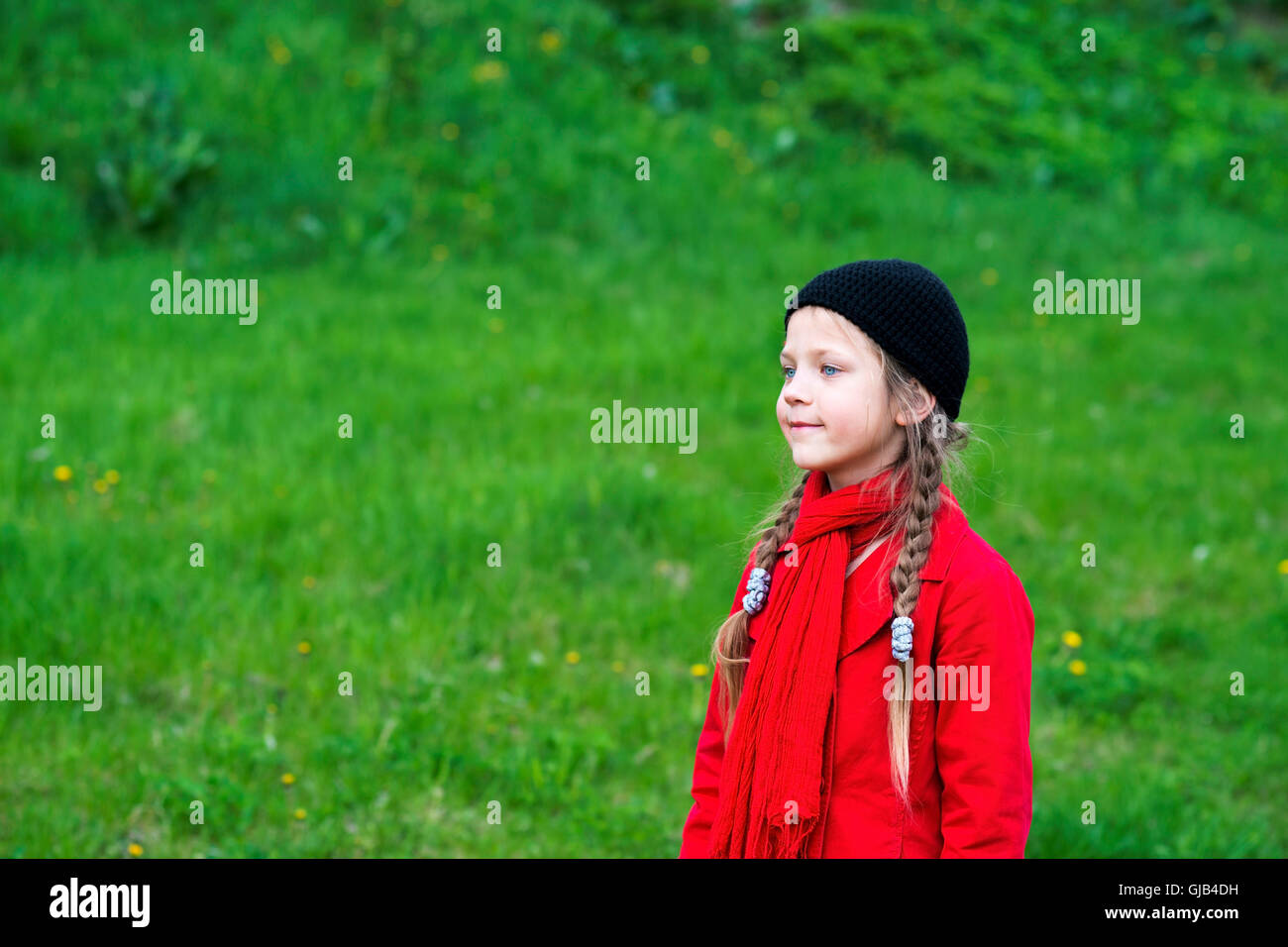 fashion girl in red raincoat by springtime on fresh green meadow Stock Photo
