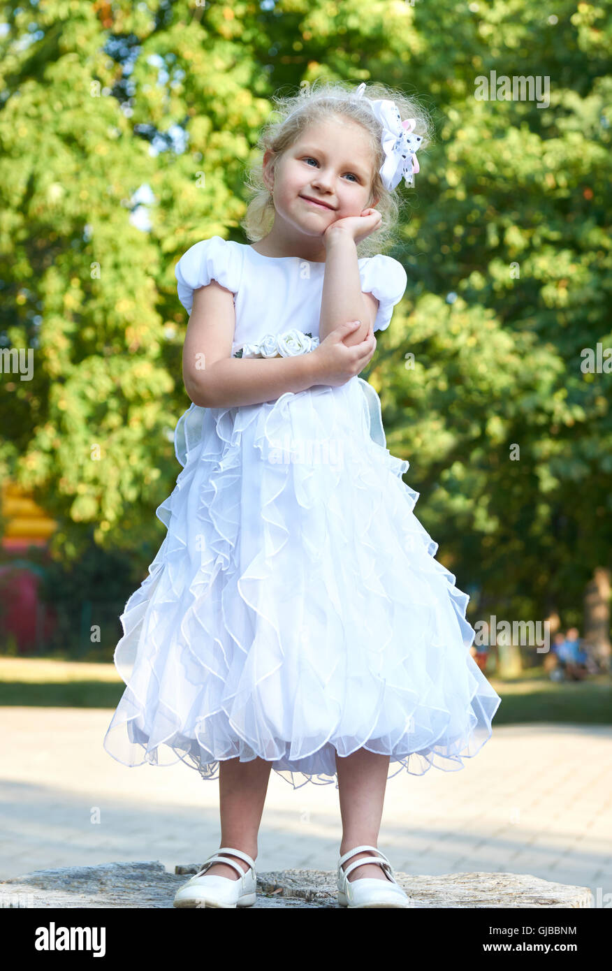 child girl in white gown, happy childhood concept, summer season in city park Stock Photo