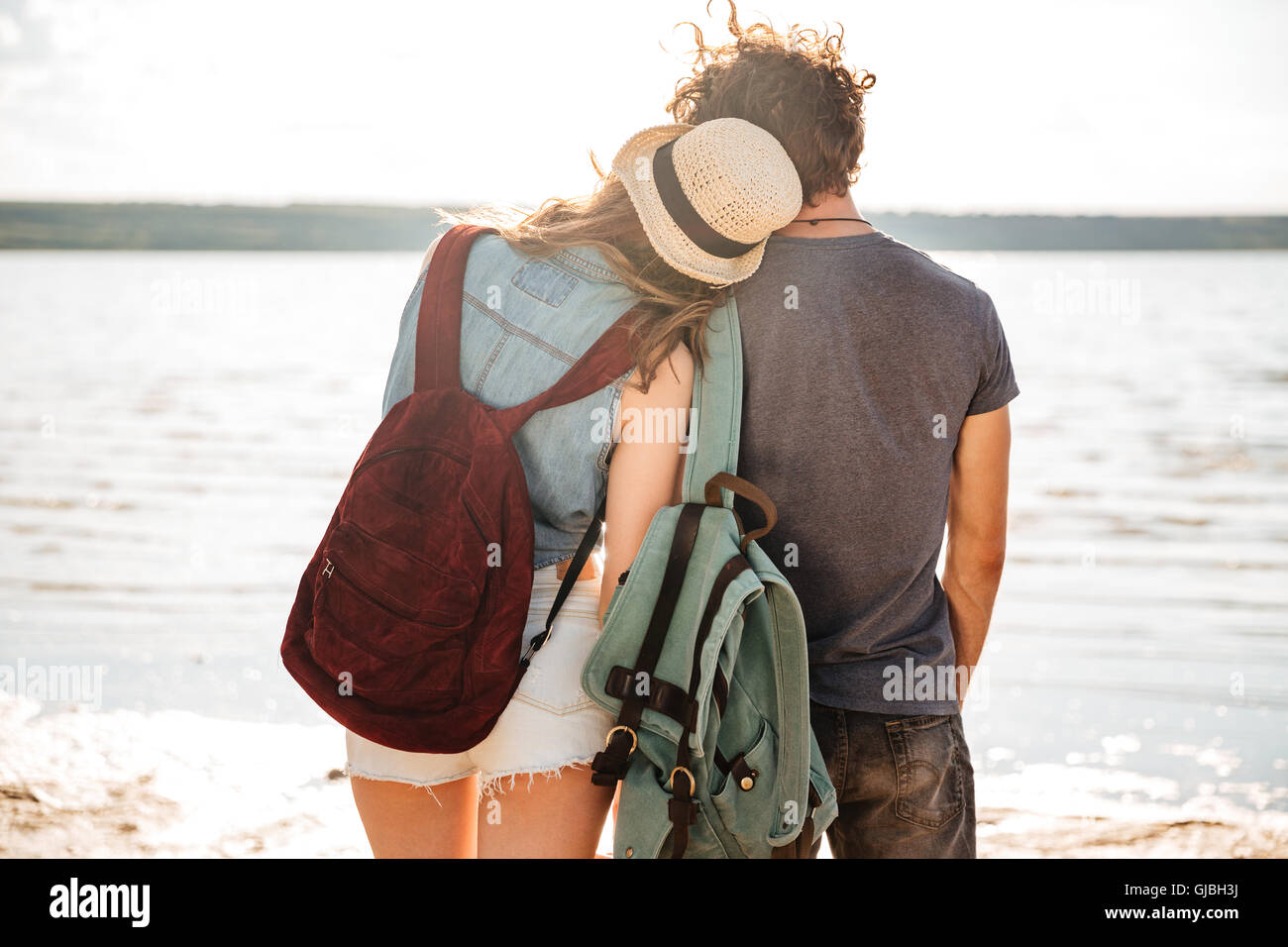 Young couple in love standing backwards hugging and looking at the seaside Stock Photo