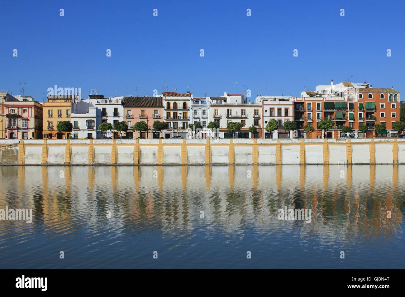 Landscape of an old city with low-rise buildings in the river coast. Guadalquivir River, Seville, Spain. Stock Photo