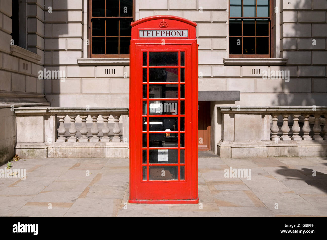 A classic red British telephone box in central London with the crown of