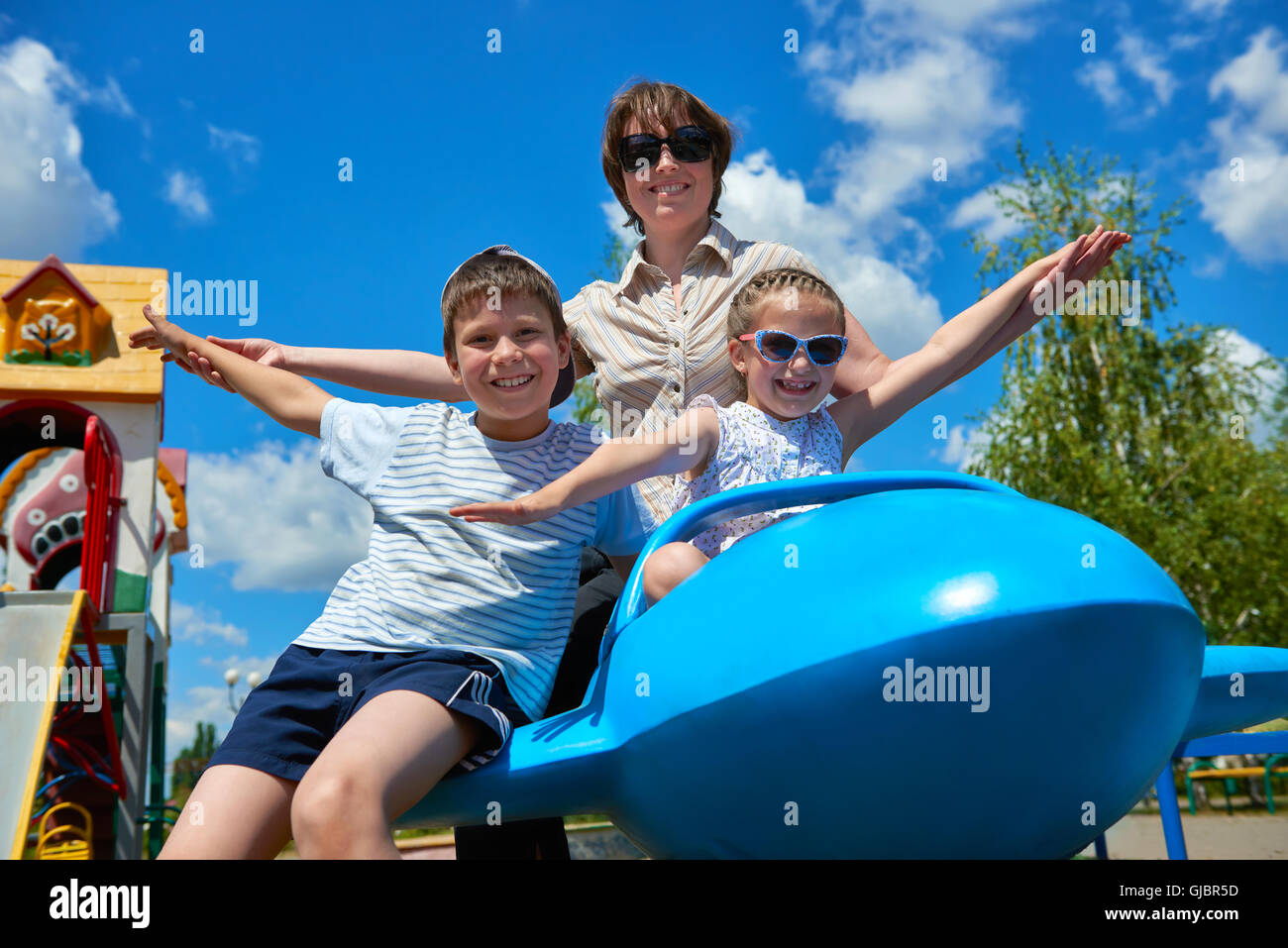 child and woman fly on blue airplane attraction in city park, happy family, summer vacation concept Stock Photo