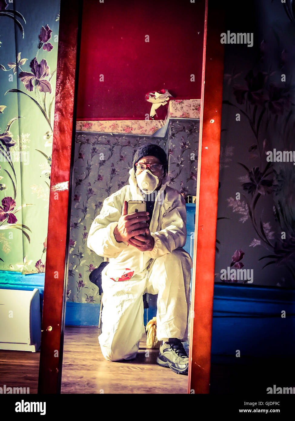 A worker in safety suit takes a selfie in front of a mirror Stock Photo
