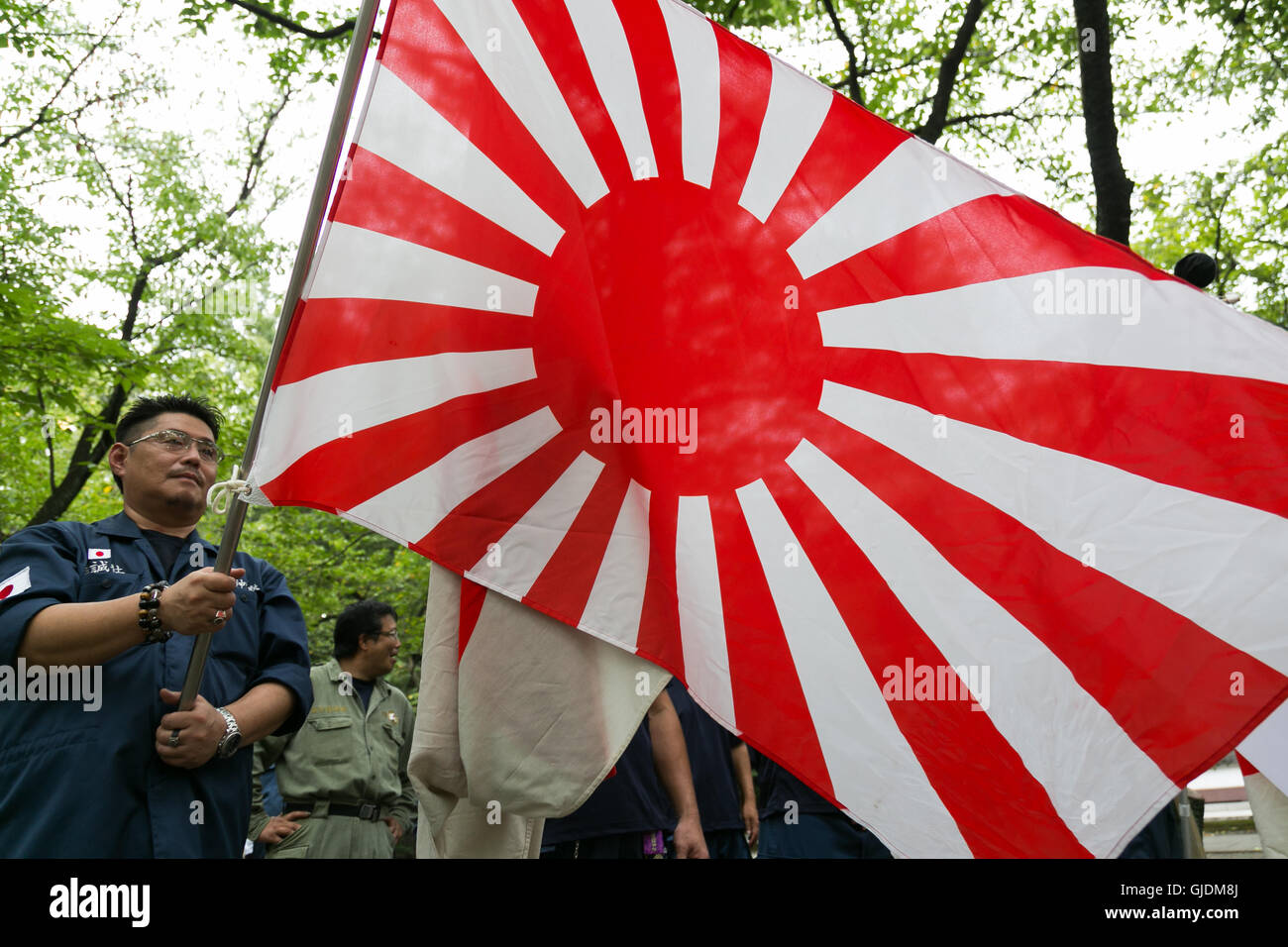 Tokyo, Japan. 15th Aug, 2016. A Japanese nationalist dressed in military uniform holds a war flag of the Imperial Japanese Army to pay his respects to the war dead at Yasukuni Shrine on the 71st anniversary of Japan's surrender in World War II on August 15, 2016, Tokyo, Japan. Some 70 lawmakers visited the Shrine to pay their respects, but the Prime Minister Shinzo Abe did not visit the controversial symbol and instead sent a ritual offering to a shrine. Credit:  Aflo Co. Ltd./Alamy Live News Stock Photo