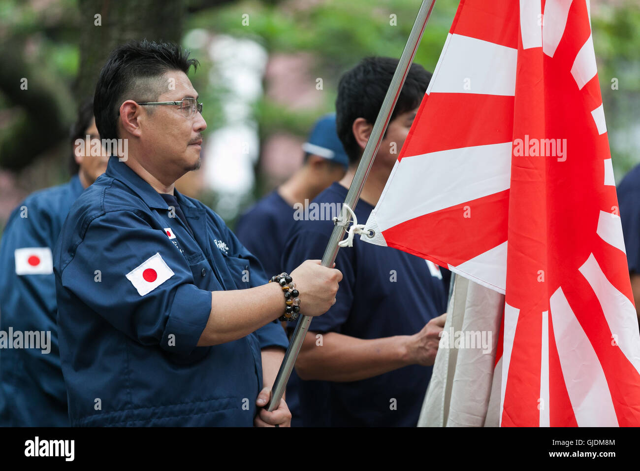 Tokyo, Japan. 15th Aug, 2016. A Japanese nationalist dressed in military uniform holds a war flag of the Imperial Japanese Army to pay his respects to the war dead at Yasukuni Shrine on the 71st anniversary of Japan's surrender in World War II on August 15, 2016, Tokyo, Japan. Some 70 lawmakers visited the Shrine to pay their respects, but the Prime Minister Shinzo Abe did not visit the controversial symbol and instead sent a ritual offering to a shrine. Credit:  Aflo Co. Ltd./Alamy Live News Stock Photo