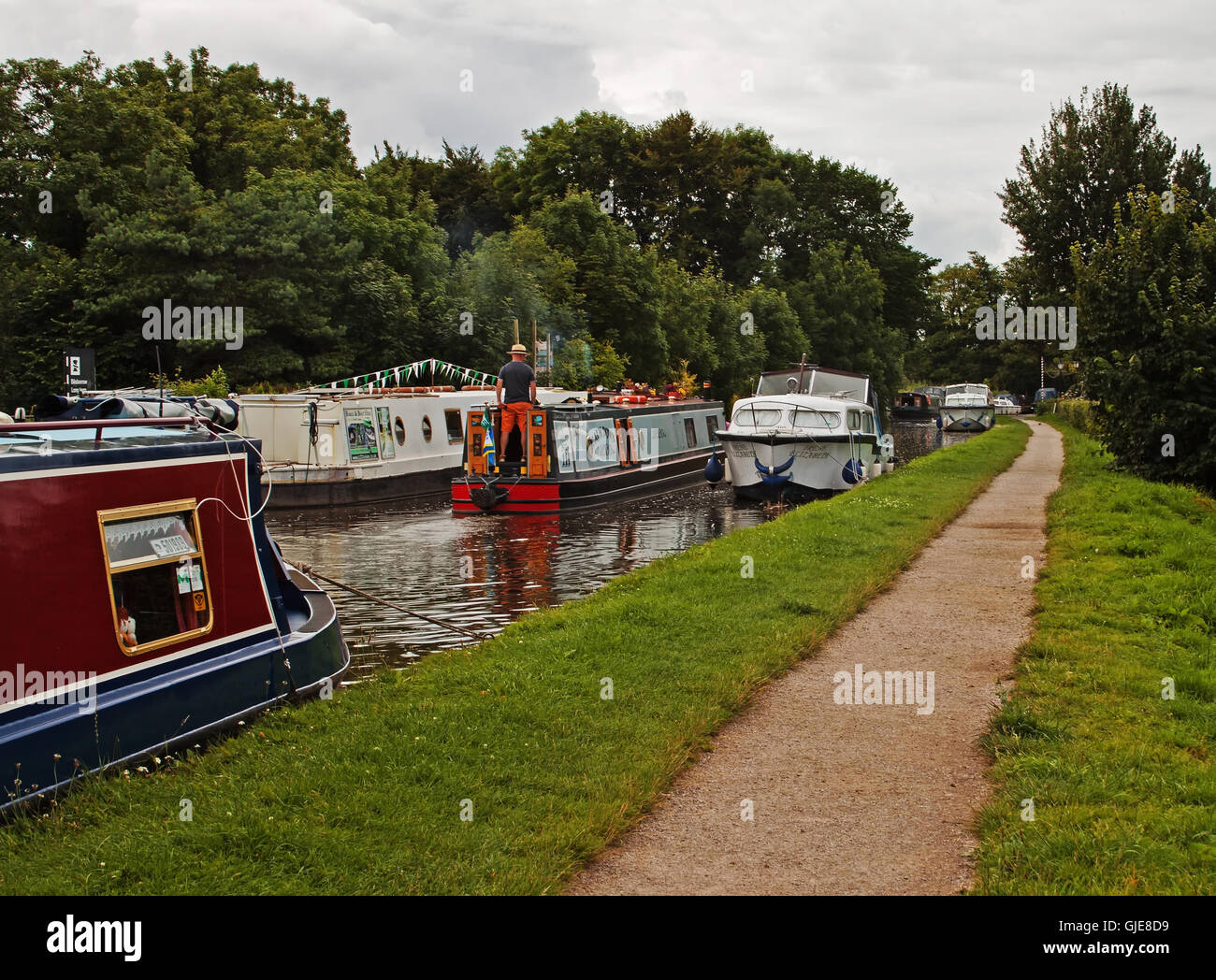 sailing by moored barges on the Lancaster Canal Stock Photo