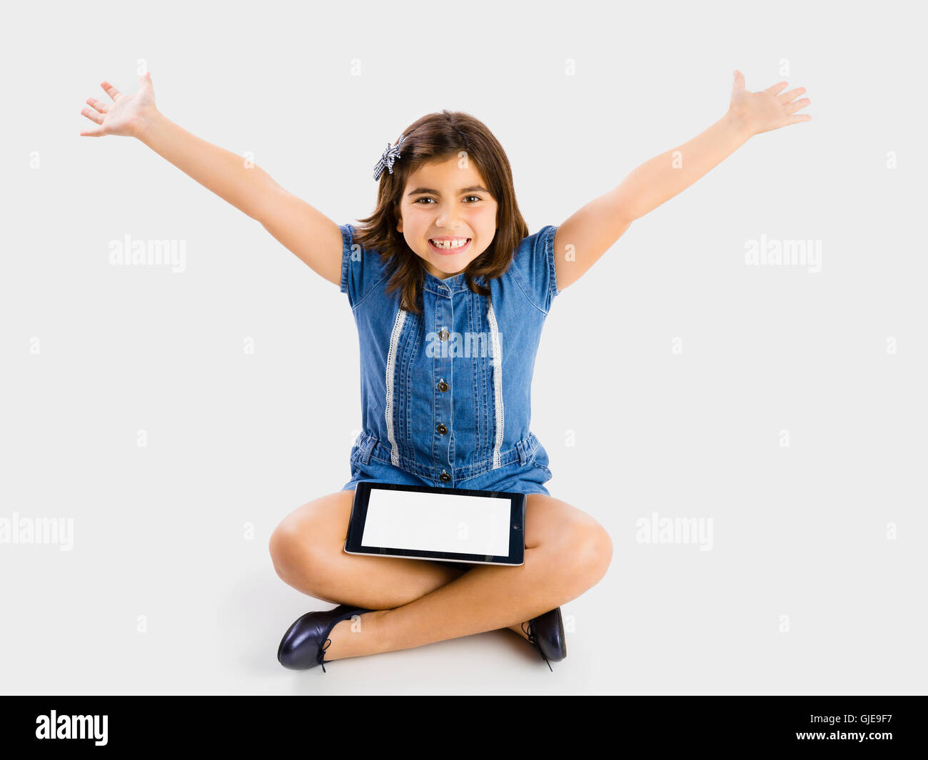 Young girl sitting on floor and using a tablet Stock Photo - Alamy