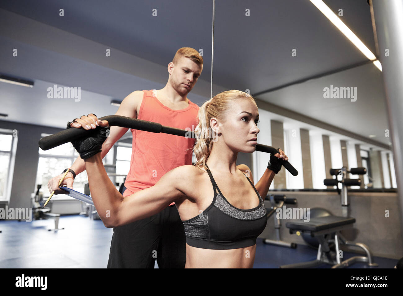 man and woman flexing muscles on gym machine Stock Photo