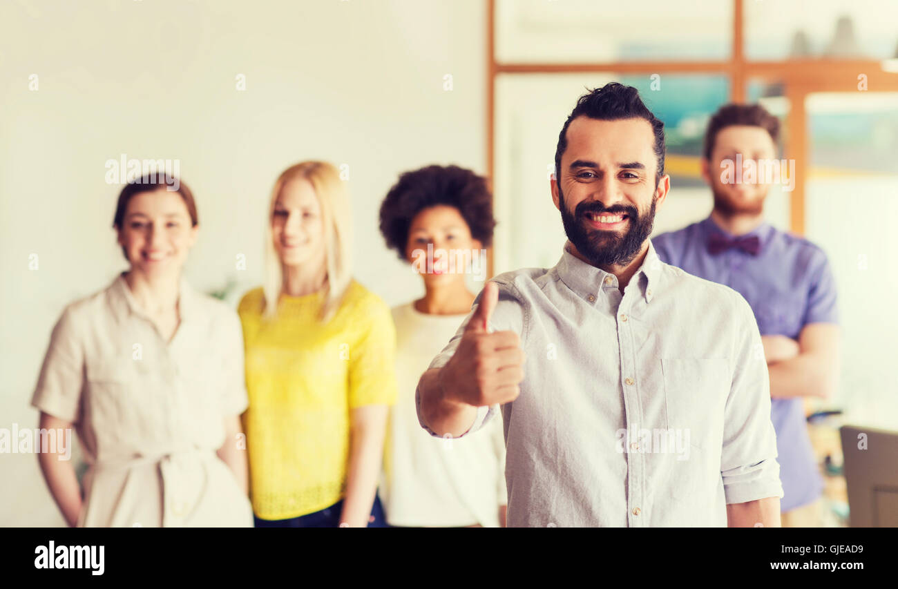 happy man showing thumbs up over team in office Stock Photo - Alamy