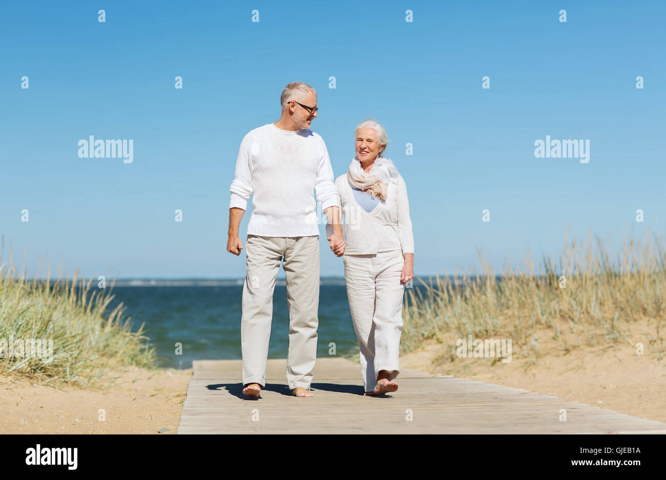 happy senior couple holding hands on summer beach Stock Photo - Alamy