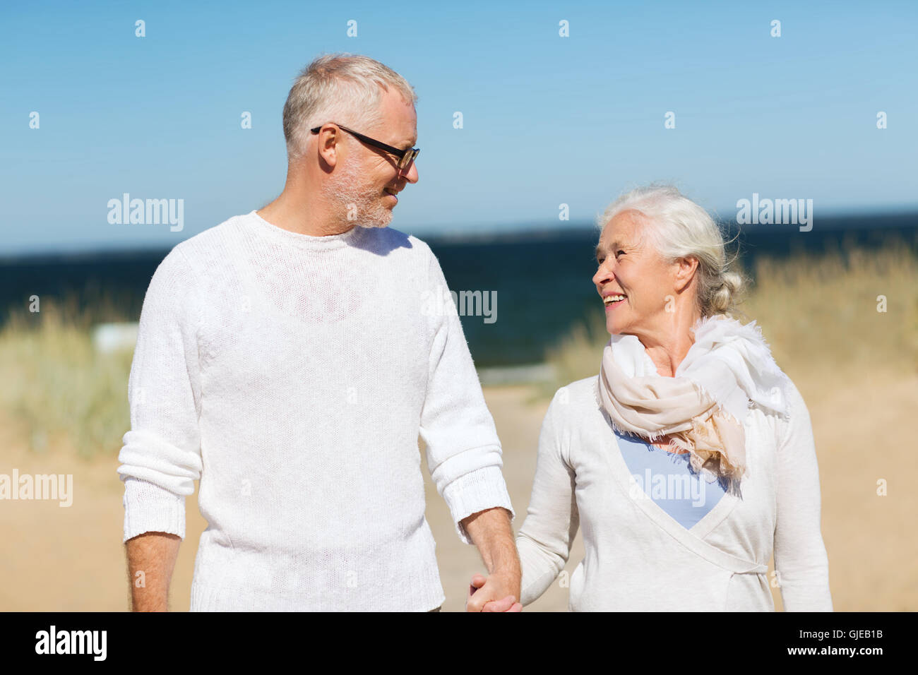 happy senior couple holding hands on summer beach Stock Photo - Alamy