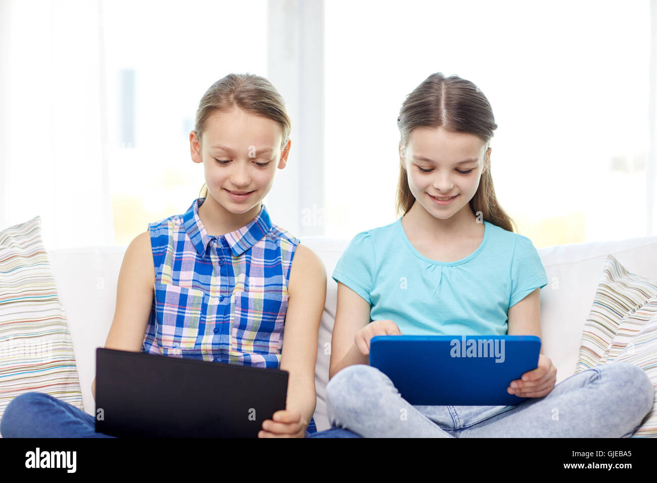 happy girls with tablet pc sitting on sofa at home Stock Photo - Alamy