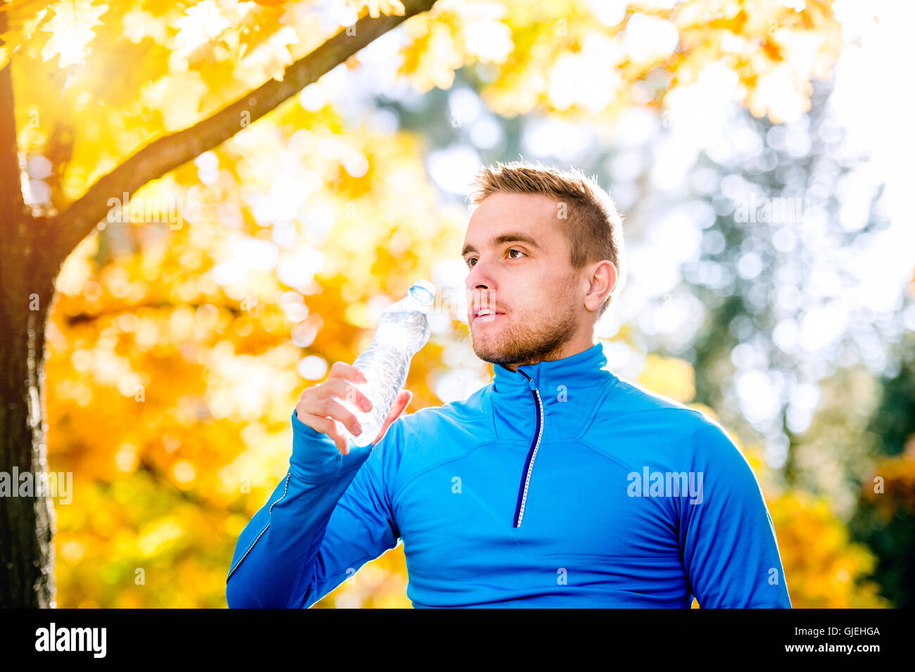 Hipster runner in autumn nature drinking water from bottle Stock Photo