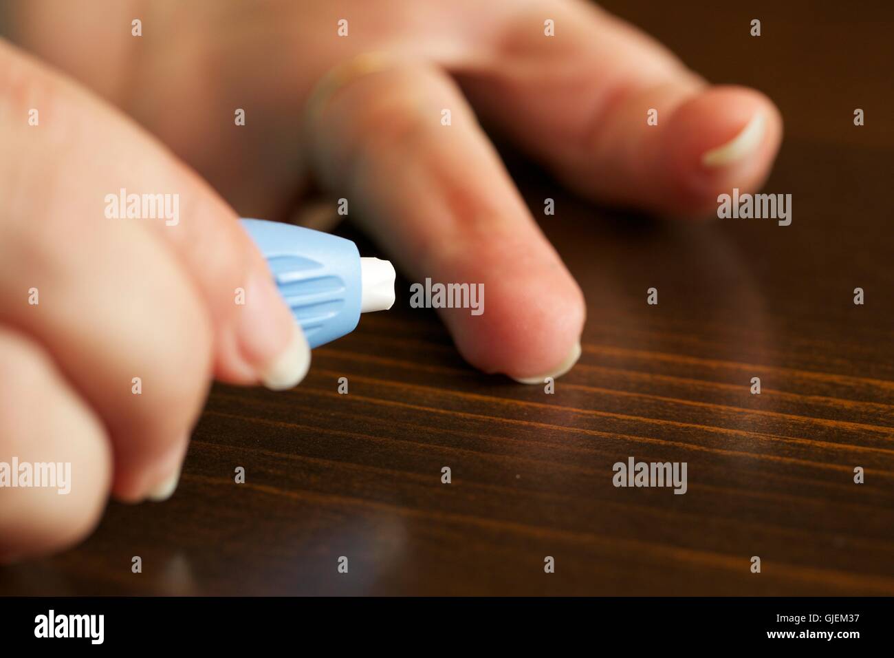 Woman using safety lancet to draw blood from finger for test. Stock Photo