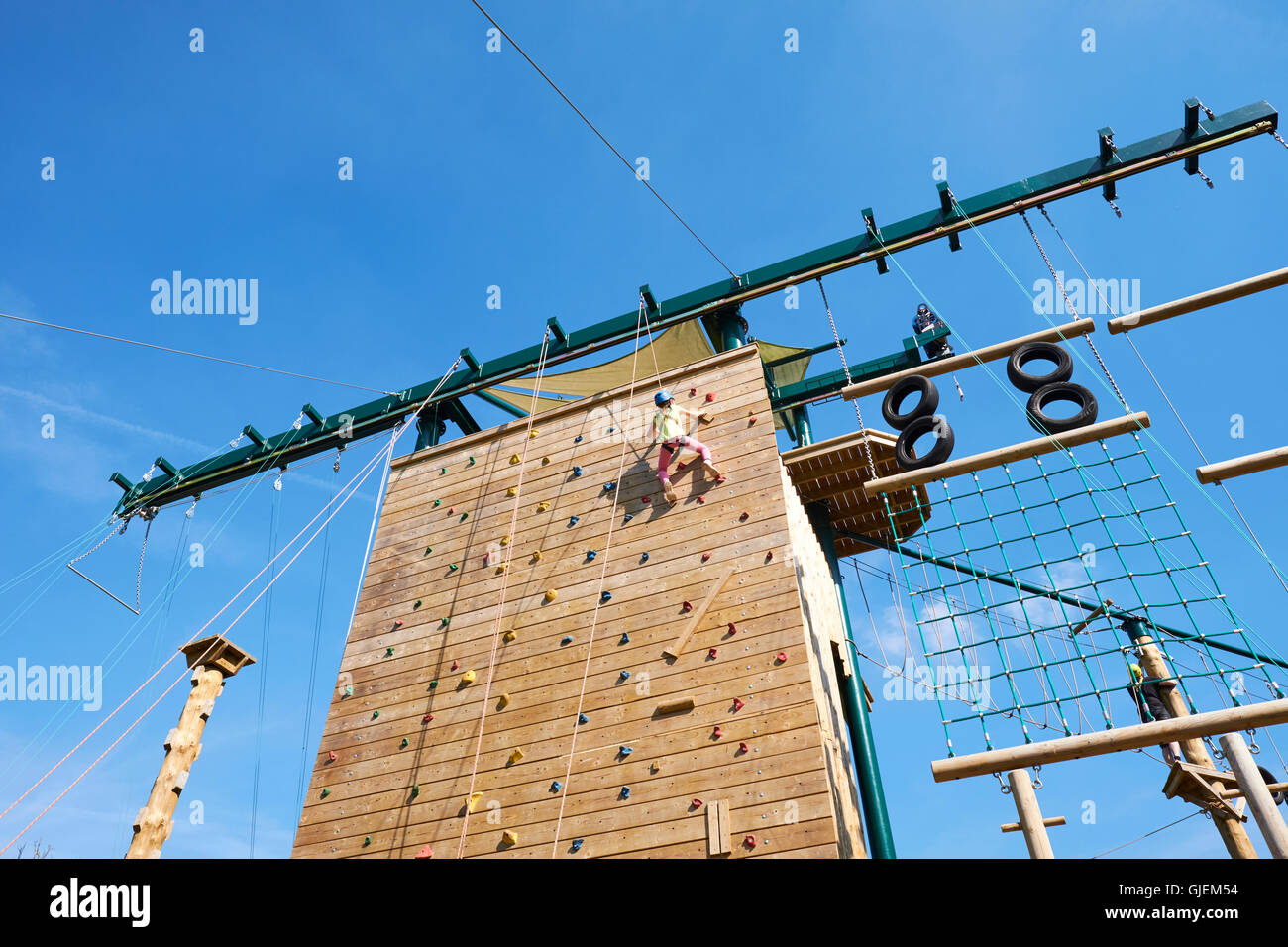 Young Girl Reaching The Top Of An Outdoor Climbing Wall At Conkers An Attraction Within The National Forest Moira Derbyshire UK Stock Photo