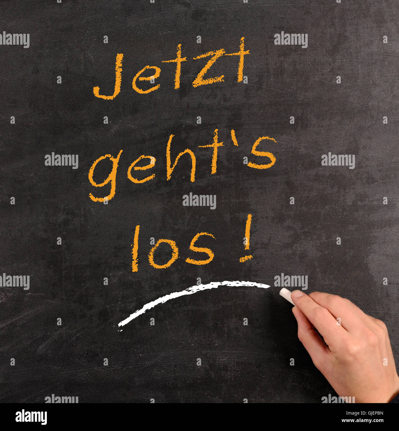 Hand writing with chalk on a blackboard the German words 'Start now!' Stock Photo