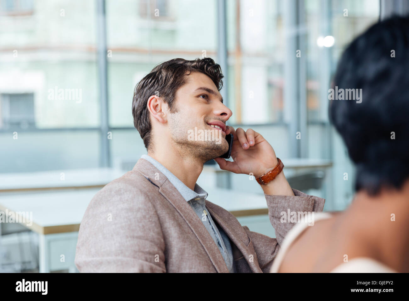 Happy handsome young man talking on cell phone in office Stock Photo