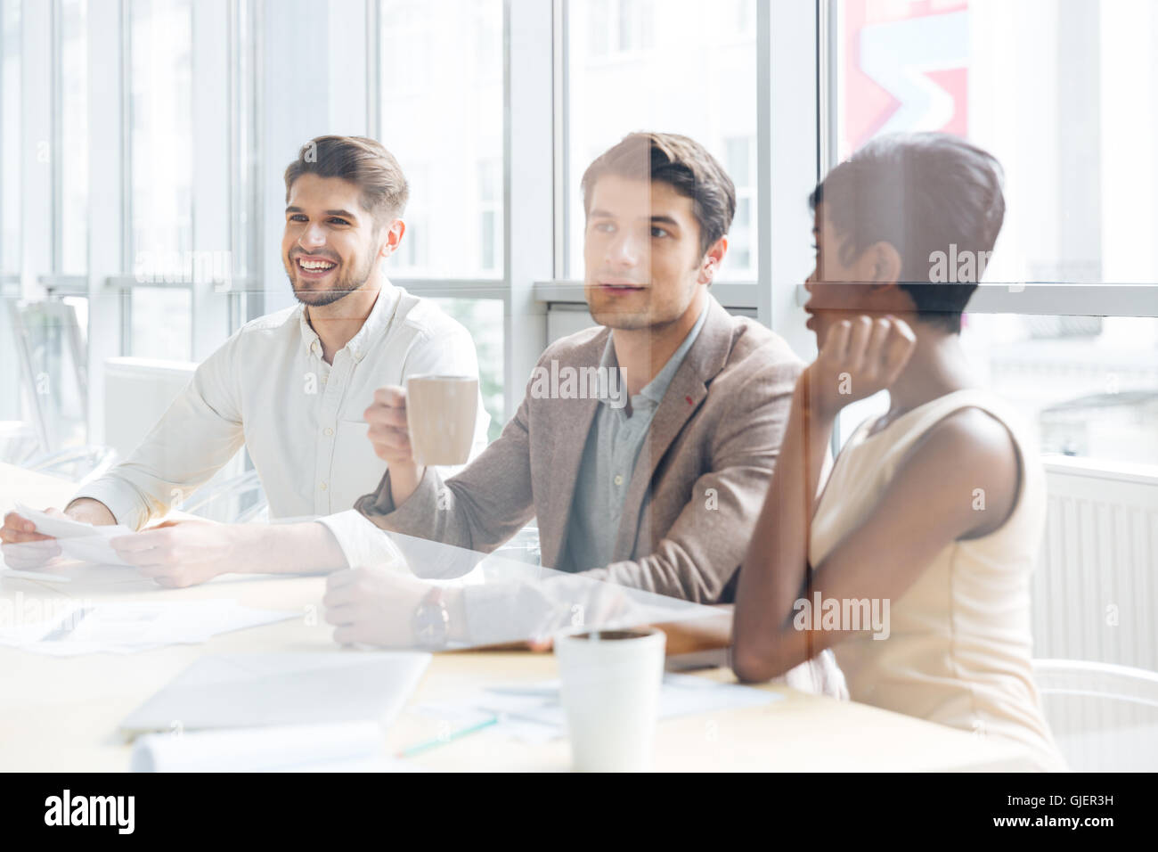 Group of cheerful young business people sitting and listening presentation in office Stock Photo