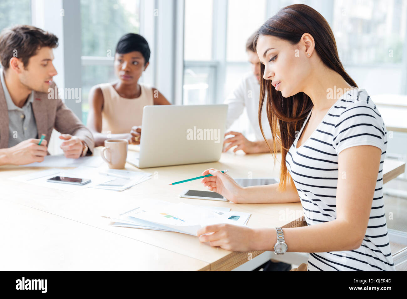 Concentrated young woman sitting and working with her business team in office Stock Photo