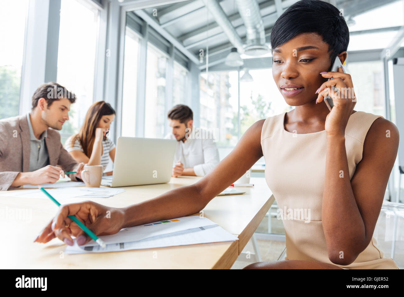 Concentrated african american young businesswoman talking on cell phone in office Stock Photo