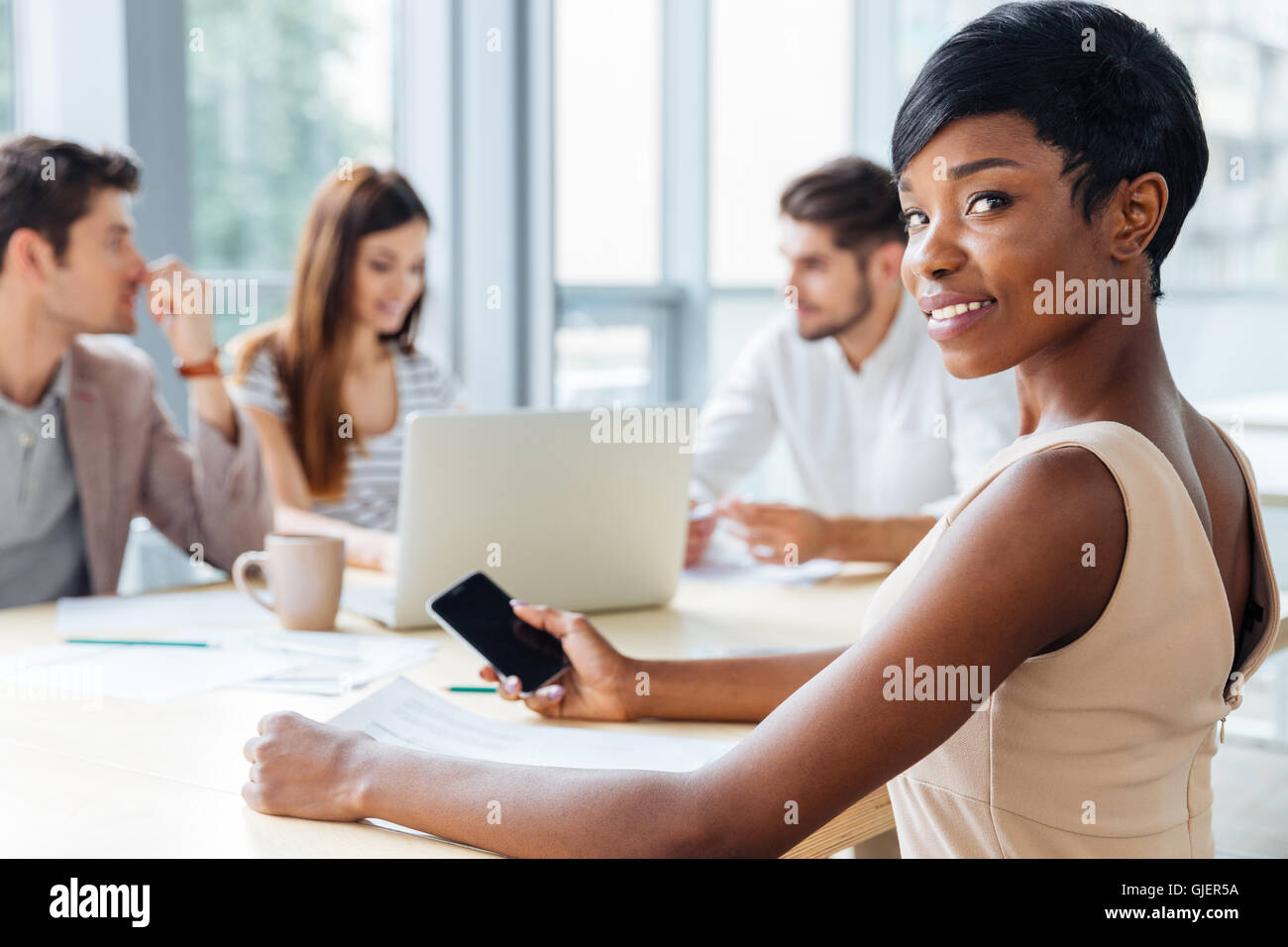 Happy african american young businesswoman using blank screen smartphone on business meeting Stock Photo