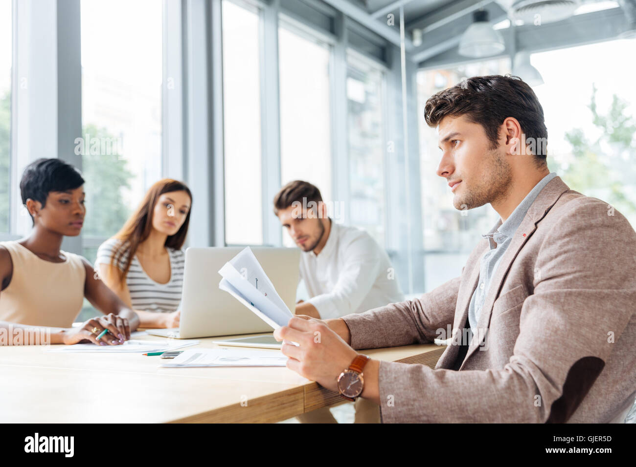 Concentrated young businessman sitting and working with his business team in office Stock Photo