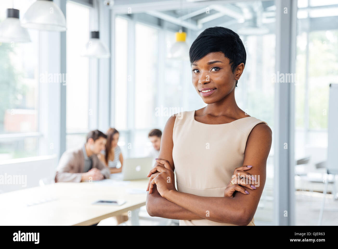 Successful african american young businesswoman standing with hands folded in office Stock Photo