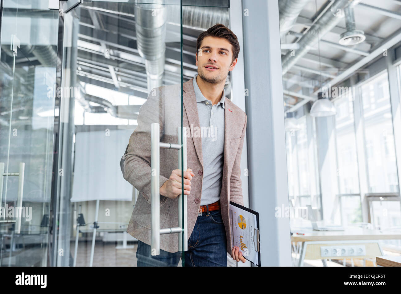 Handsome Young Businessman With Clipboard Entering The Door In Office Stock Photo Alamy