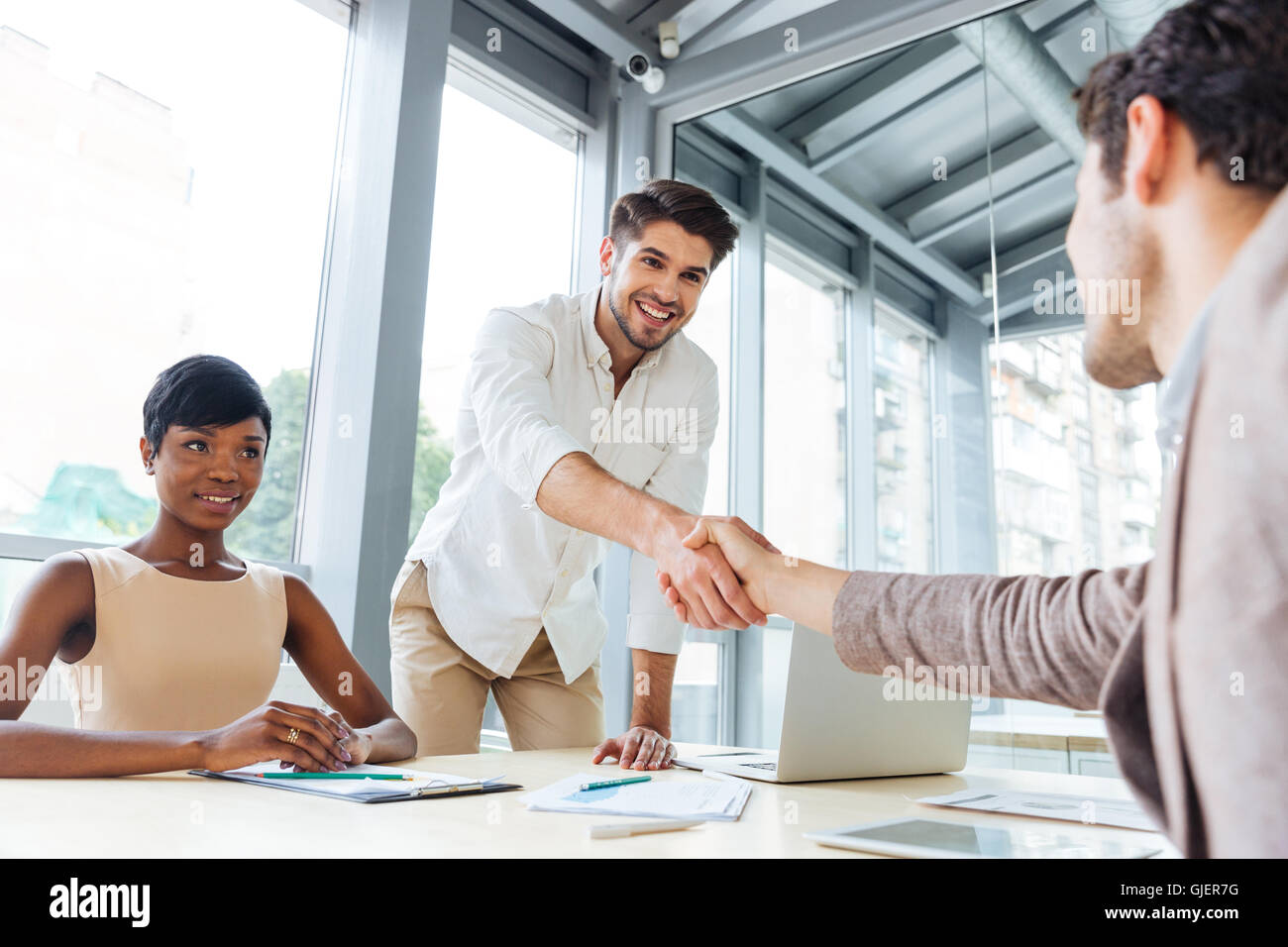 Two young businessmen shaking hands and ending business meeting in office Stock Photo