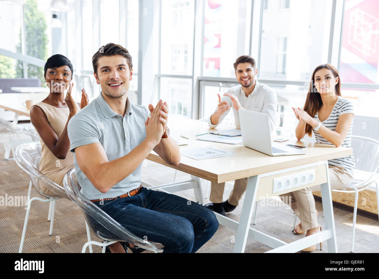 Group of cheerful young business people sitting on presentation in office and clapping Stock Photo
