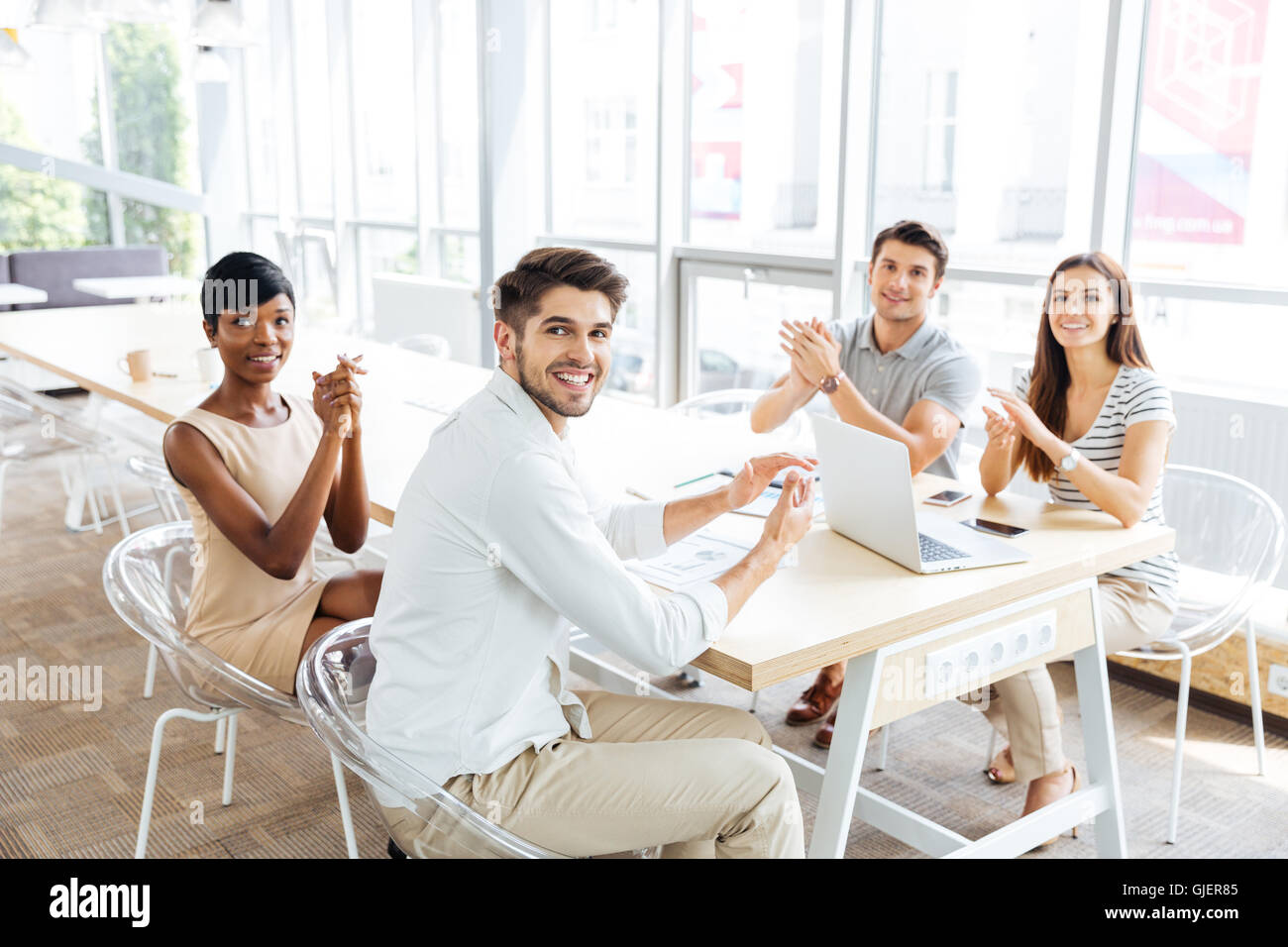 Group of cheerful young business people sitting and clapping hands during presentation in office Stock Photo
