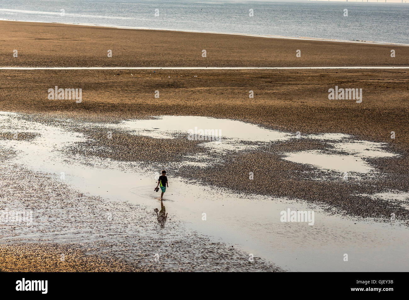 A solitary youngster walking on a beach. Stock Photo